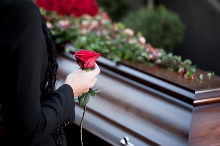 Funeral. mujer sostiene una rosa delante de un ataúd