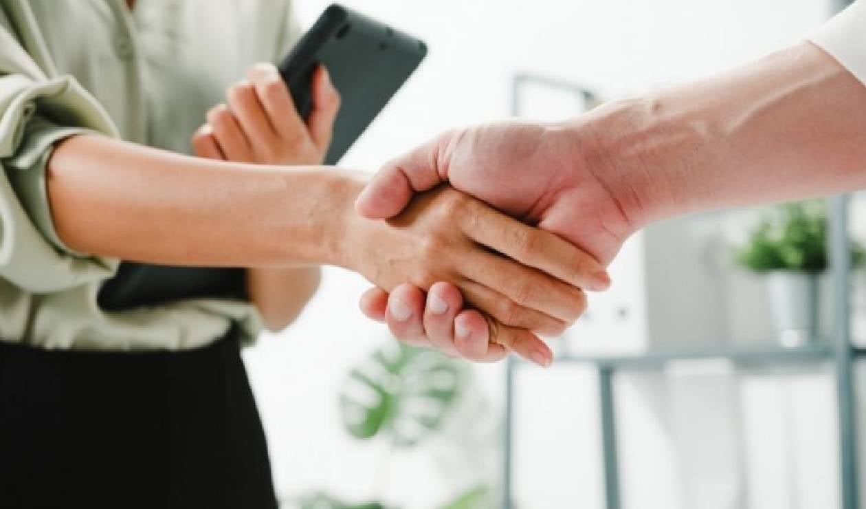 Dos personas estrechando su mano y cerrando un contrato de trabajo