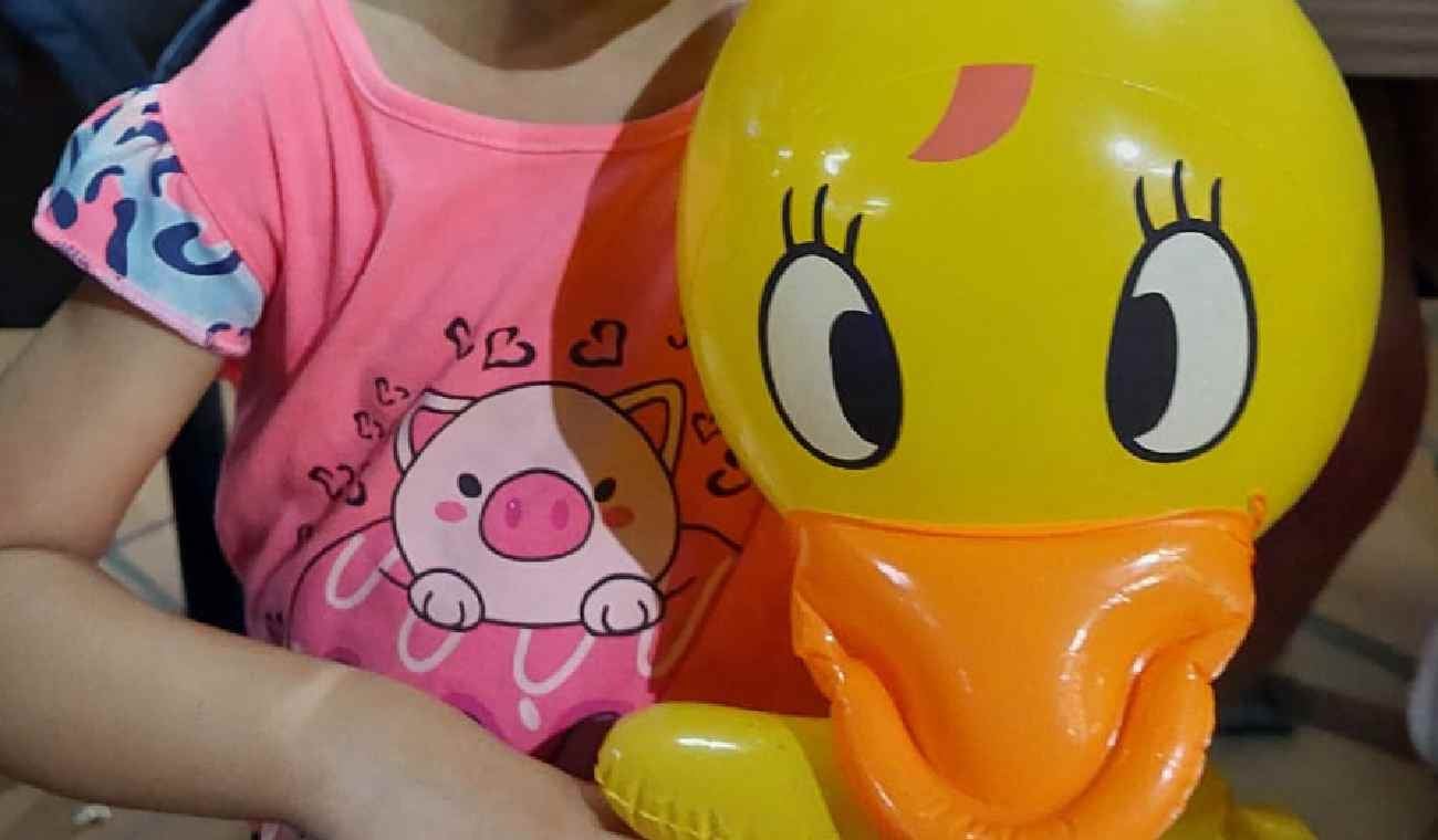 Niña con pato plástico en la mano