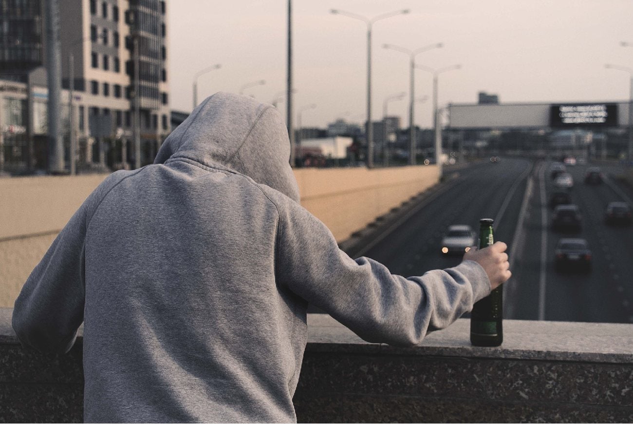 Hombre en un puente con una botella de alcohol en su mano
