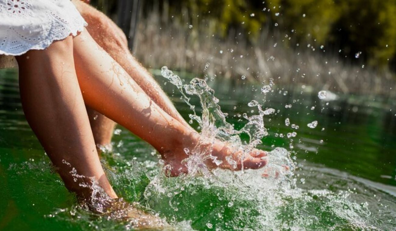 Pies de dos personas en el borde de una piscina de agua termal