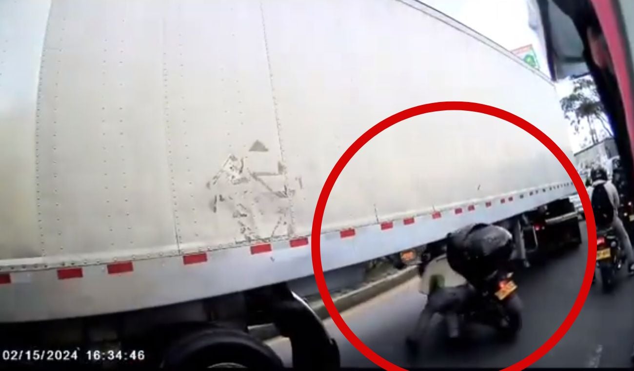 Motociclista tratando de pasar debajo de una tractomula en Bogotá