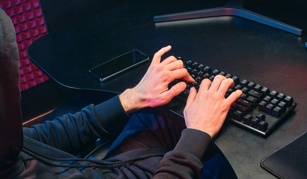 Hombre incógnito escribiendo en un computador para estafar a la gente