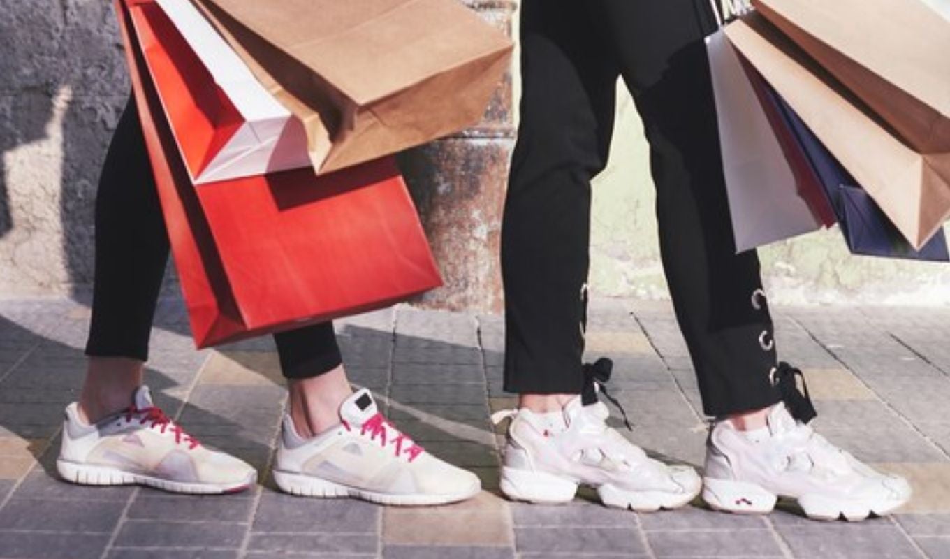 Dos personas usando tenis llevando bolsas de compra
