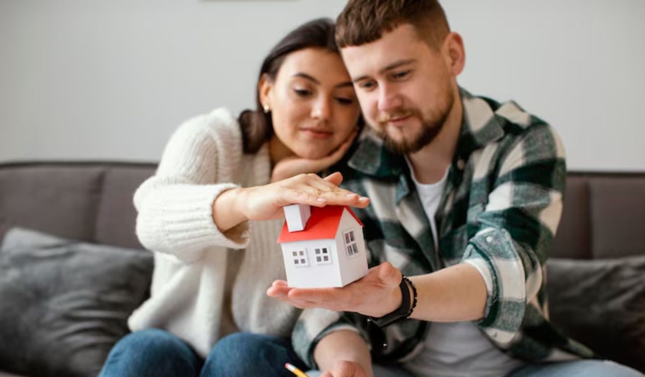 Pareja sosteniendo una maqueta de casa
