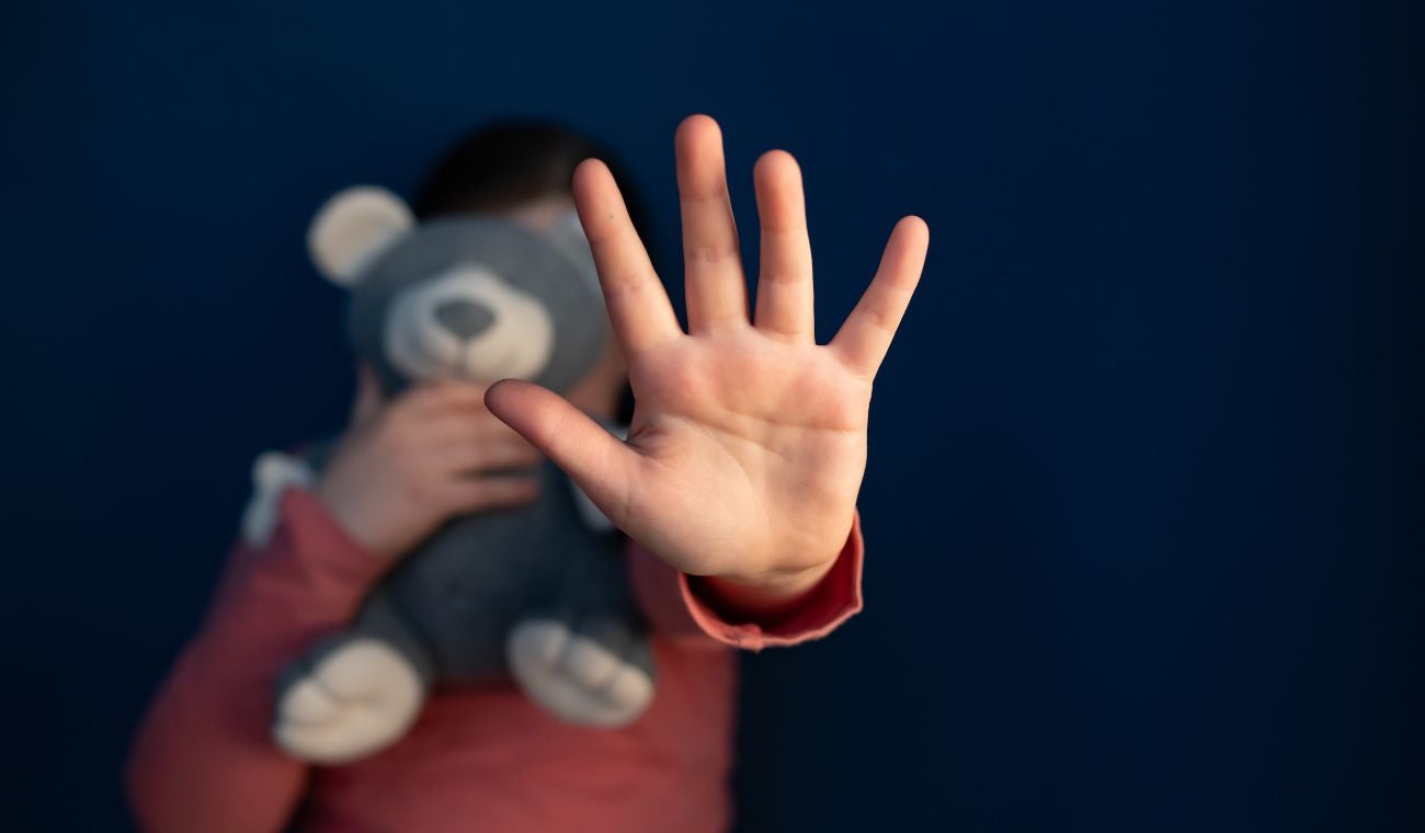 Menor tapándose la cara con un peluche