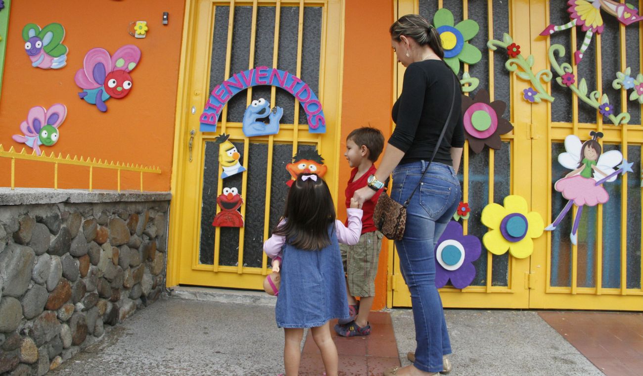Mujer llevando a sus hijos al jardín infantil