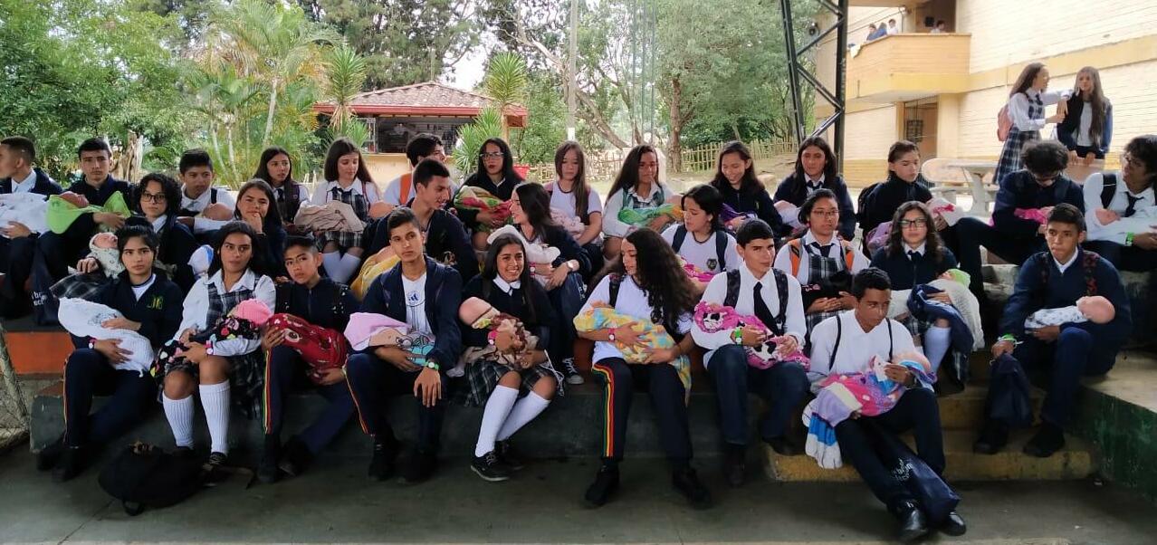 Jóvenes cuidan a un bebé robot en Caldas, Antioquia.