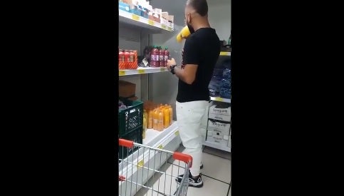 Hombre tomando de varias botellas de jugo en una tienda D1.