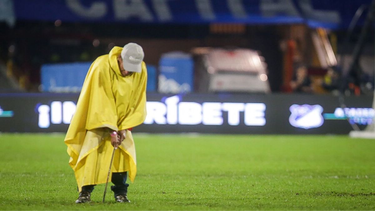 Hombre de logística intentando drenar agua de la cancha en El Campín