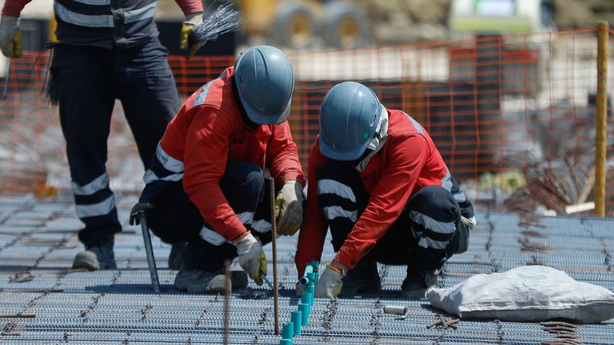 Dos trabajadores de la construcción amarrando hierro