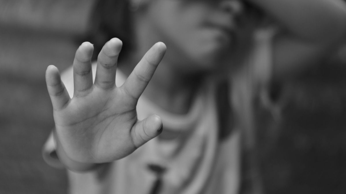 Menor extendiendo la mano y tapándose el rostro