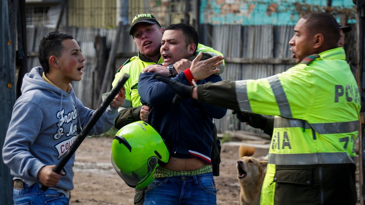 Policías intentando detener una riña en Bogotá, forcejeando con dos hombres