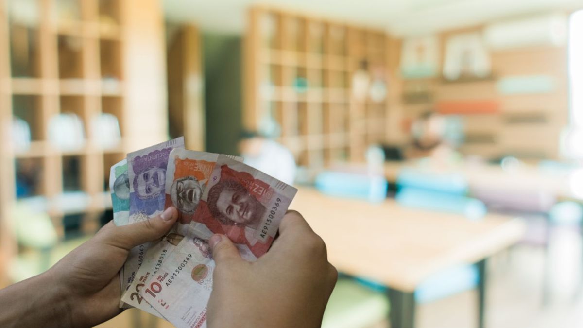 Persona contando dinero y de fondo un salón de clases