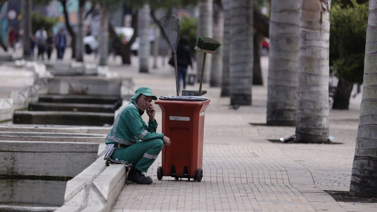 Operario de aseo y barrido en Bogotá descansando en una acera