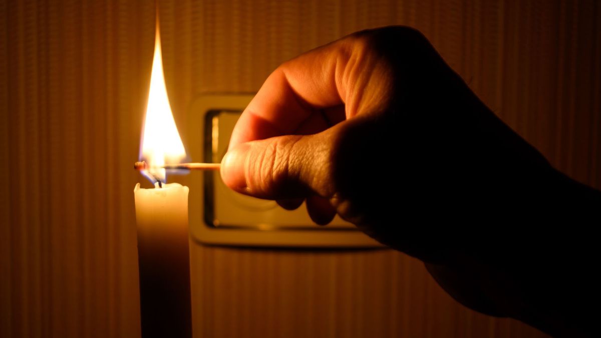Hombre prendiendo una vela por un corte de luz