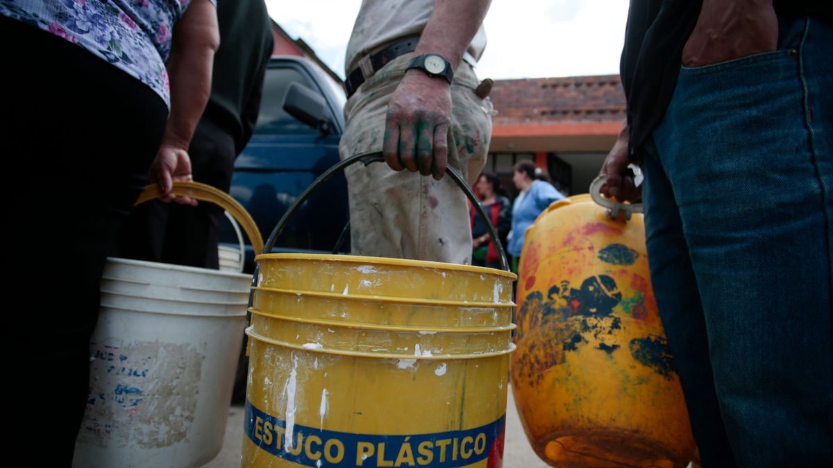 Ciudadanos haciendo fila para recoger agua con baldes