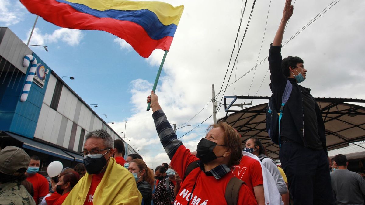 Personas levantando una bandera de Colombia en una protesta