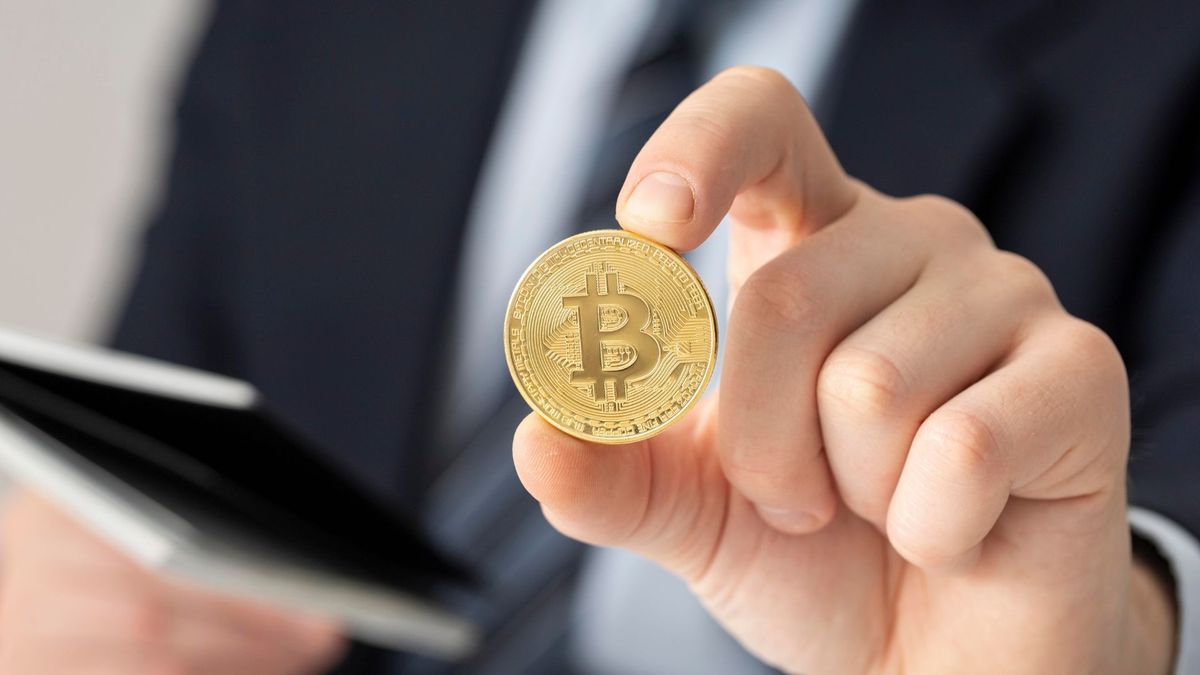 Hombre sosteniendo una moneda de Bitcoin