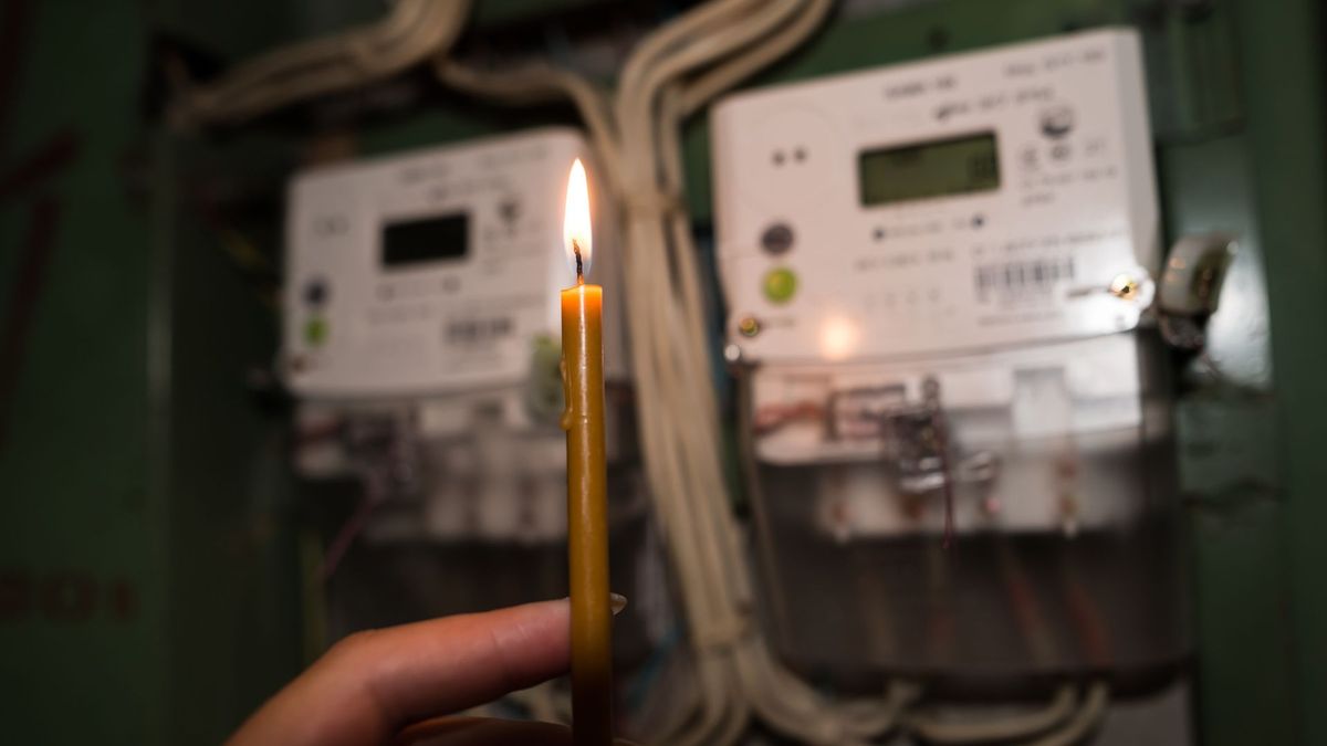 Medidor de electricidad y hombre alumbrando con una vela