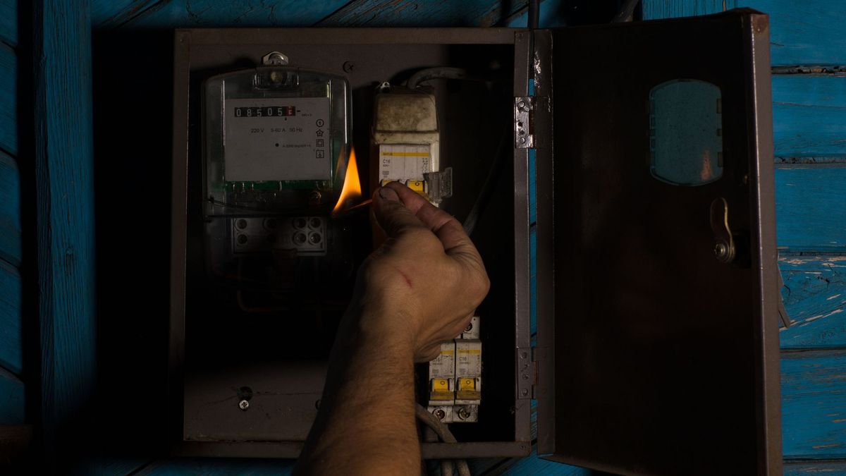 Hombre alumbrando contador de energía con un fósforo