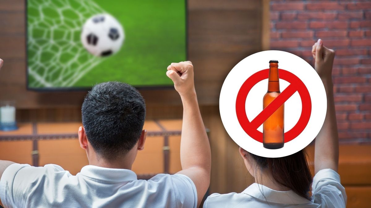 Personas viendo un partido y señal de prohibido tomar bebidas alcohólicas