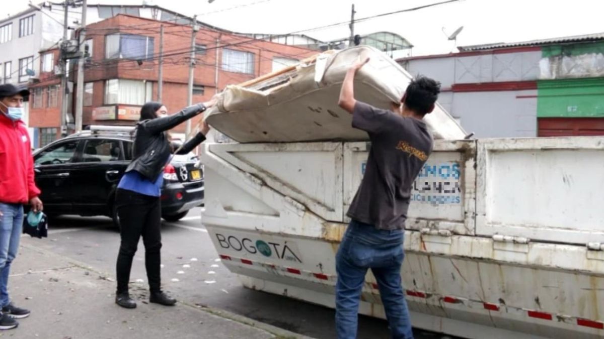 Personas tirando un colchón en un ecopunto
