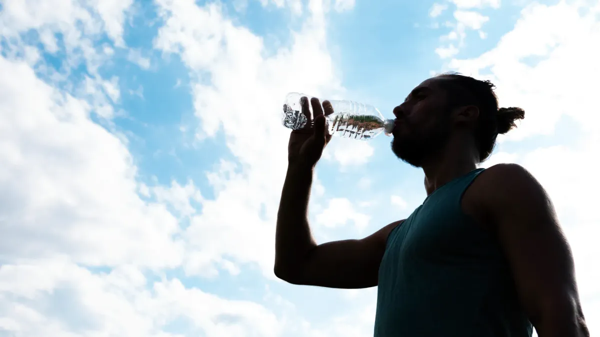 Fotografía de un hombre tomándose una botella de agua por las altas temperaturas.