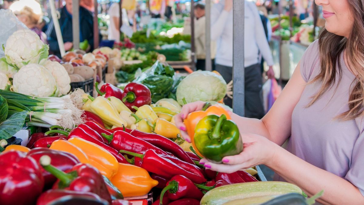 Mujer escogiendo verduras en plaza de mercado