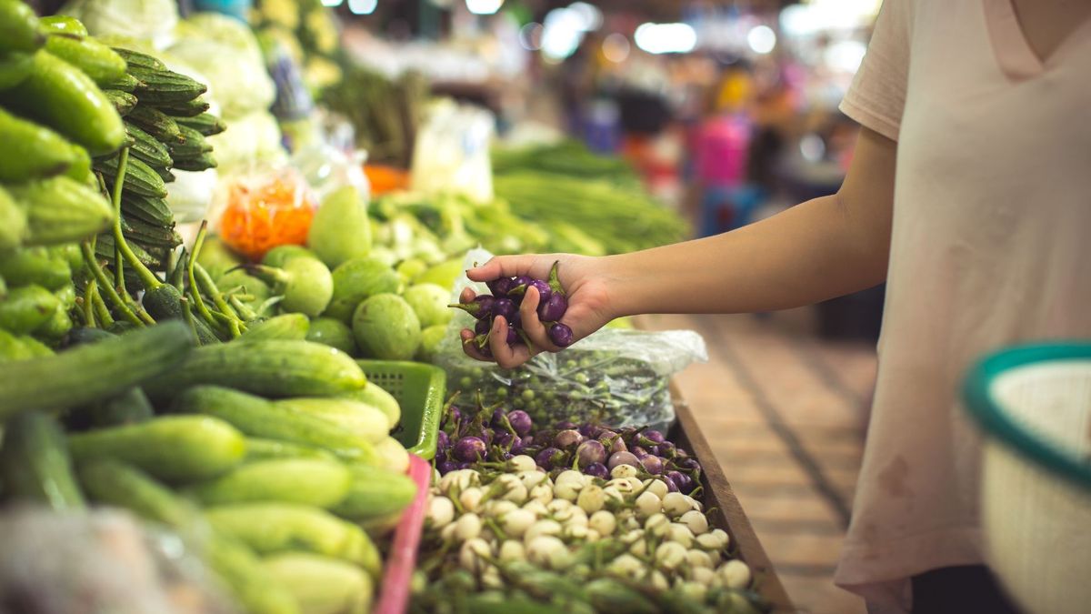 Persona escogiendo verduras en plaza de mercado