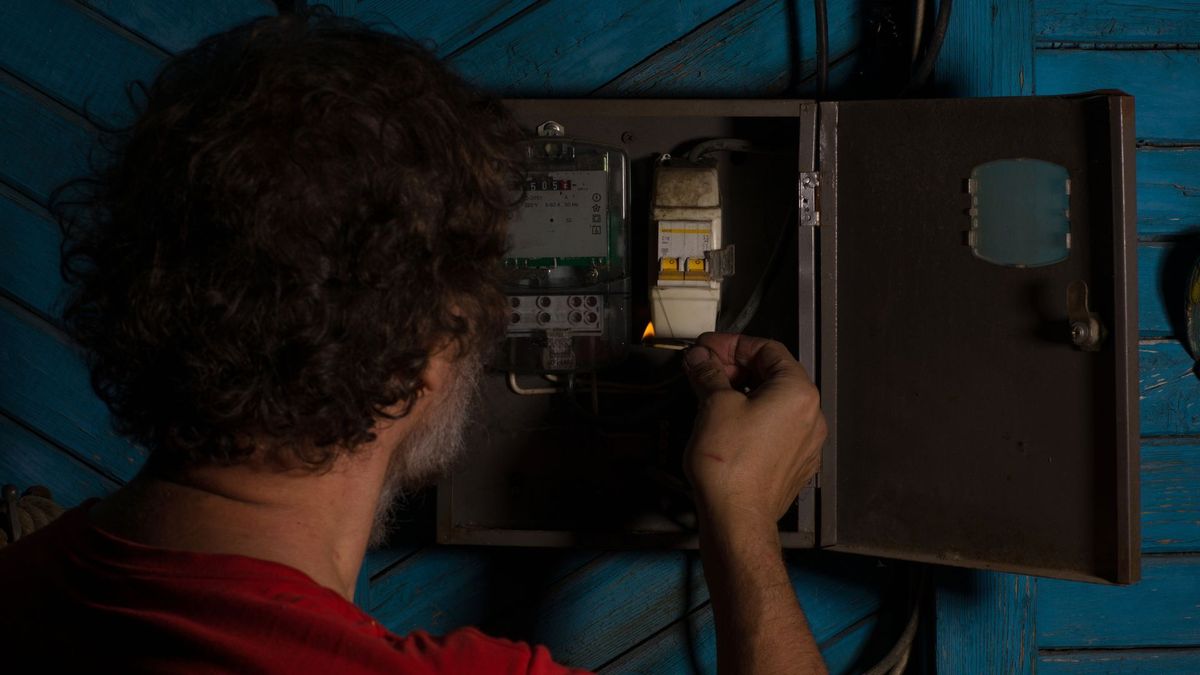Hombre alumbrando tablero de energía